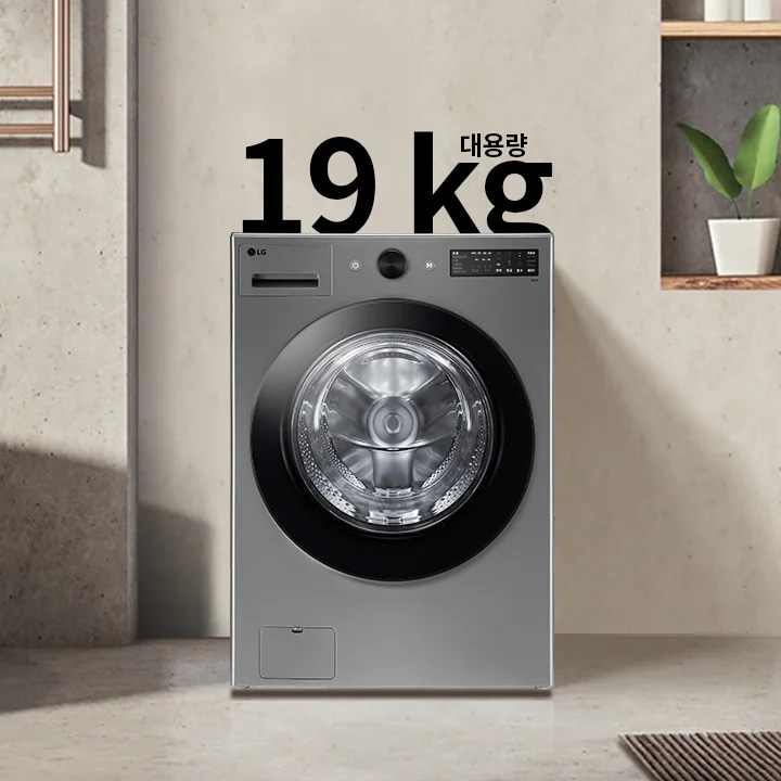 세탁기가 욕실에 놓여 있으며, 세탁기 위에는 19kg 대용량이라는 텍스트가 있습니다. 세탁기 옆에는 욕조와 수건이 걸려 있고, 벽 선반에는 식물과 용기가 놓여 있습니다.