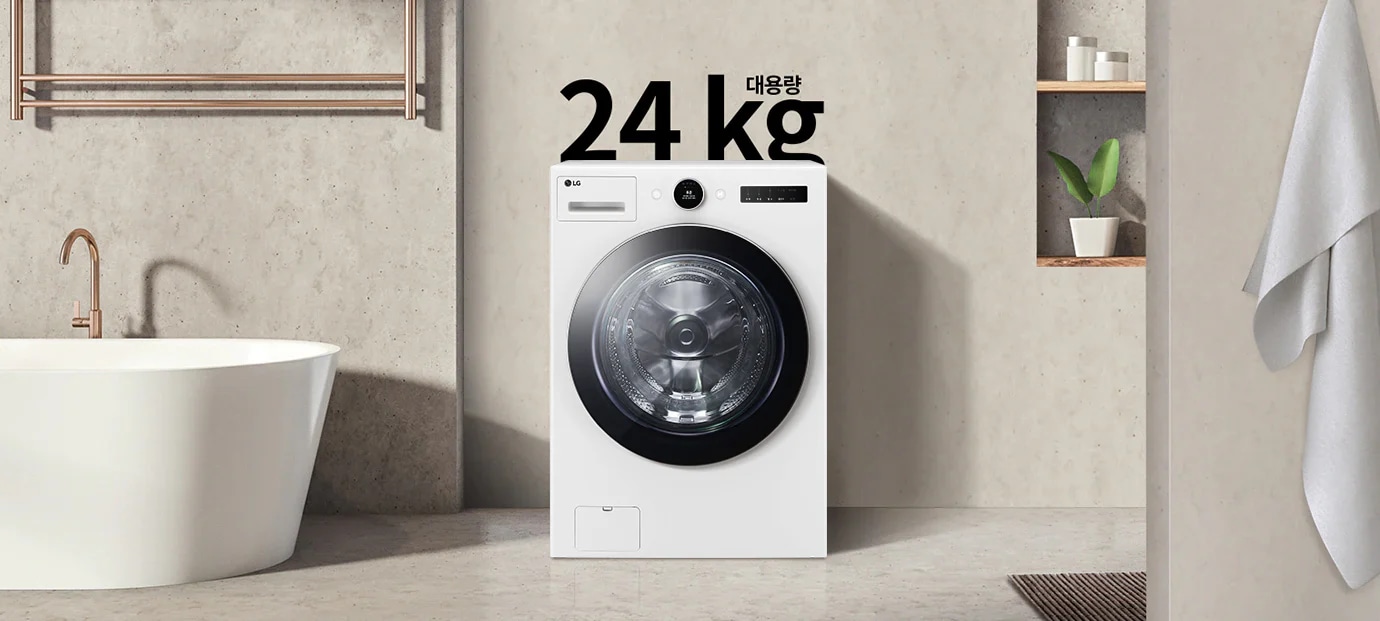 세련된 욕실 공간에 대형 세탁기가 놓여 있으며, 세탁기 위에는 "대용량 24 kg"이라는 문구가 적혀 있습니다. 세탁기 주변에는 욕조와 수건이 걸려 있고, 벽 선반에는 화분과 용기가 놓여 있습니다.