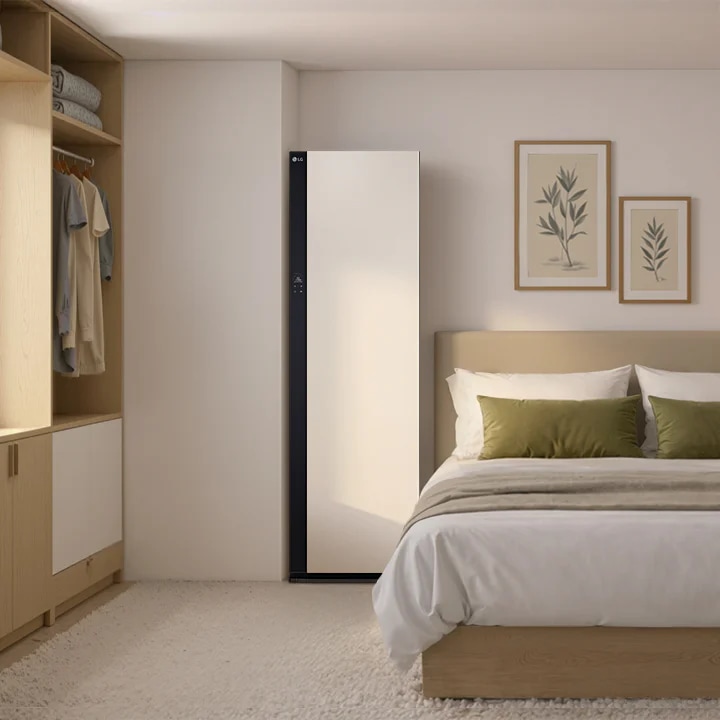 베이지톤 실내공간 중심에 스타일러가 놓여있습니다. 우측에는 침대, 좌측에는 옷장이 있습니다. 