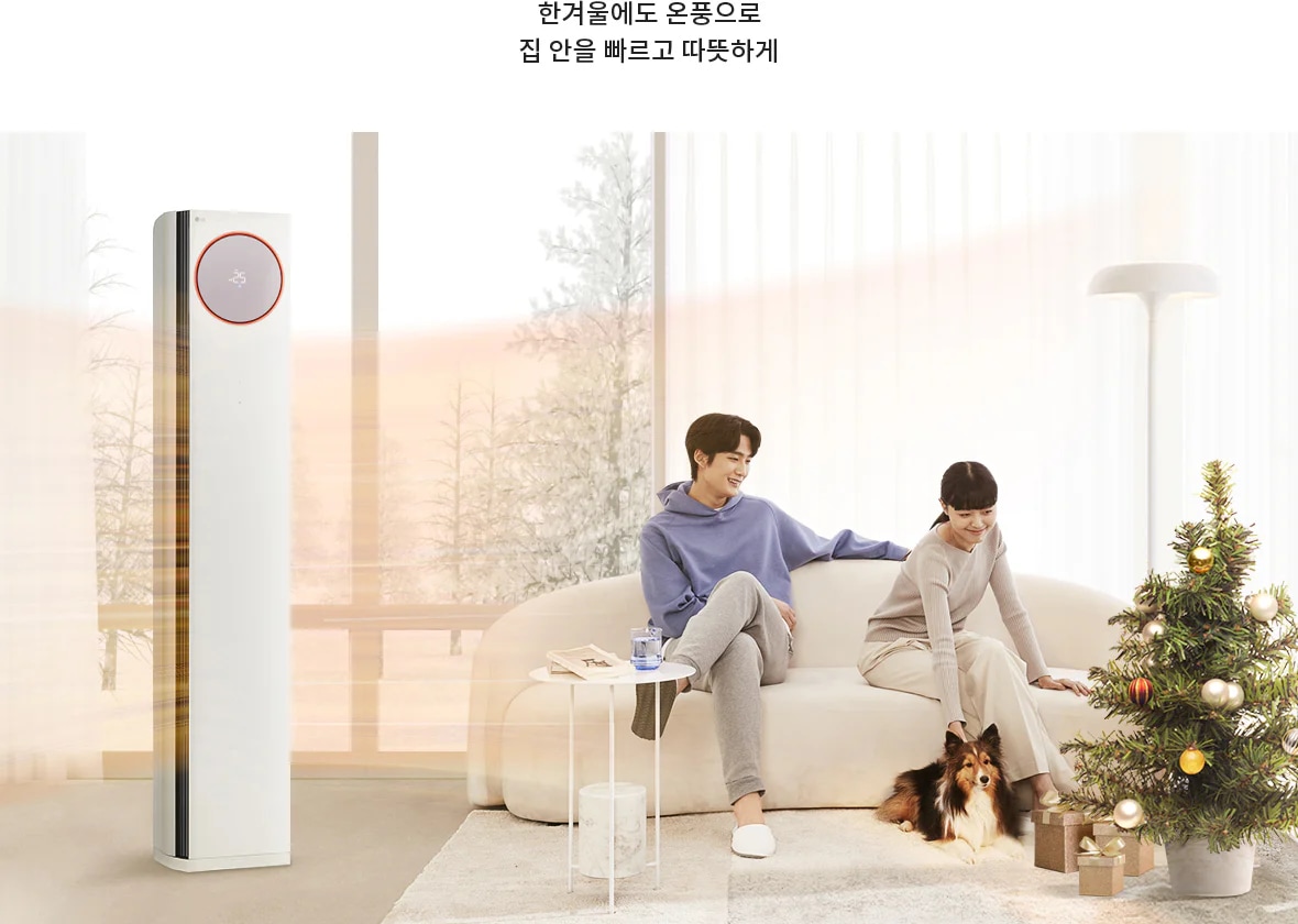 한겨울에도 온풍으로 집 안을 빠르고 따뜻하게. 두 사람이 소파에 앉아 있고, 작은 강아지가 함께 있으며, 크리스마스 트리가 장식되어 있습니다. 창밖으로는 눈 덮인 나무들이 보이고, 실내에는 에어컨이 놓여 있습니다.