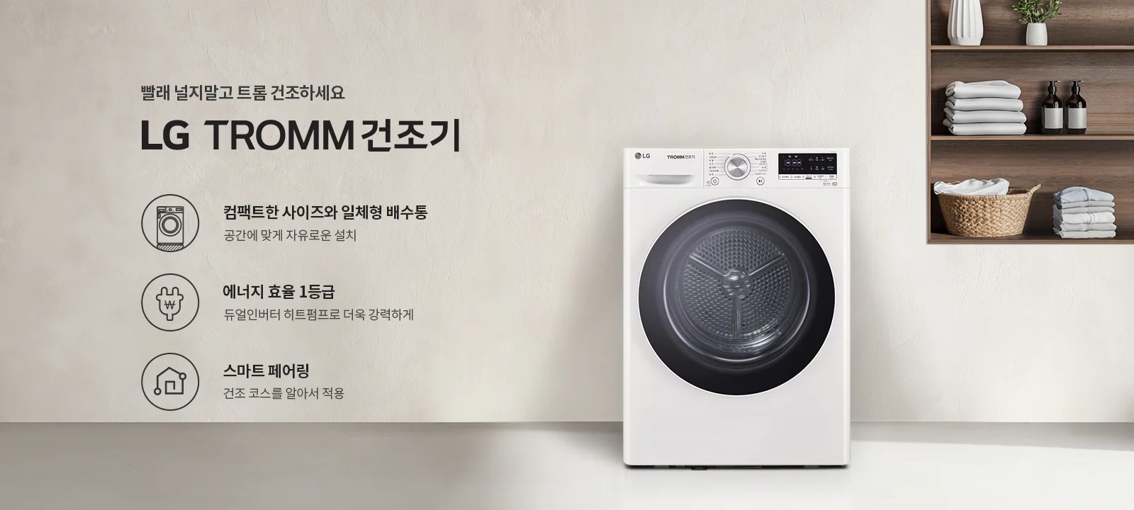 빨래 널지말고 트롬 건조하세요. LG TROMM 건조기. 컴팩트한 사이즈와 일체형 배수통, 공간에 맞게 자유로운 설치. 에너지 효율 1등급, 듀얼인버터 히트펌프로 더욱 강력하게. 스마트 페어링, 건조 코스를 알아서 적용. 흰색 건조기가 있고, 옆 선반에는 접힌 수건과 장식품이 놓여 있습니다.