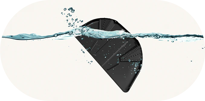 검은색 반원형 물체가 물속에 잠겨 있으며, 물방울이 물체 주변에 퍼져 있는 모습입니다. 물은 투명하고 물체의 일부를 덮고 있으며, 물체 표면에는 선형 패턴이 보입니다. 