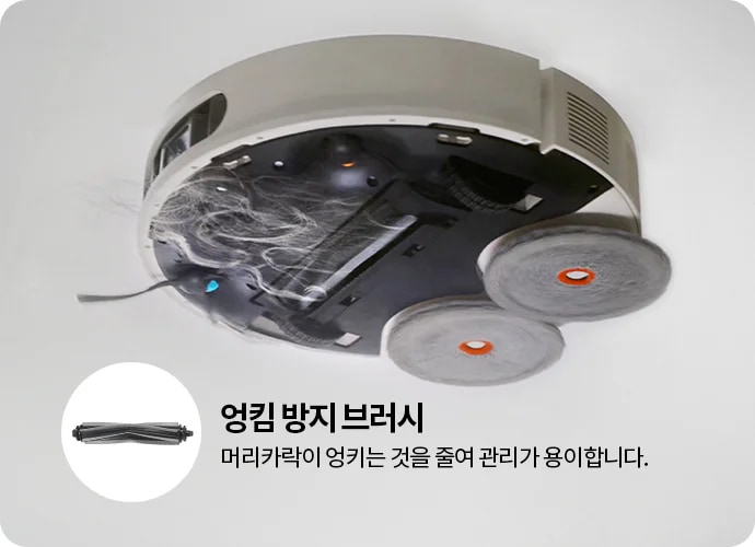 로봇 청소기의 하단 모습이 보이며, 청소기 내부에 머리카락이 엉킨 모습이 있습니다. 두 개의 회전 브러시가 장착되어 있으며, 엉킴 방지 브러시라는 텍스트와 함께 머리카락이 엉키는 것을 줄여 관리가 용이합니다.라는 설명이 포함되어 있습니다. 브러시의 확대 이미지도 함께 제공됩니다.