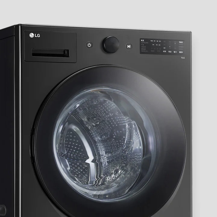 검은색 LG 세탁기가 보입니다. 세탁기 전면에 투명한 문이 있으며, 내부 드럼이 보입니다. 상단에는 전원 버튼과 조작 다이얼이 있고, 디지털 디스플레이 화면이 있습니다. 디스플레이에는 다양한 세탁 옵션이 표시되어 있습니다.