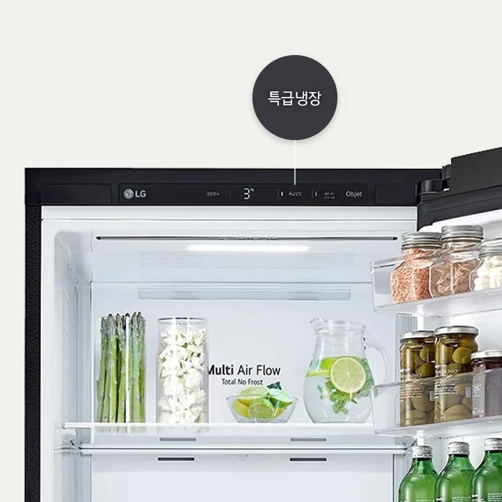 LG 로고가 있는 냉장고 내부 모습이 보입니다. 상단에는 특급냉장이라는 텍스트가 있으며, 온도는 3도로 설정되어 있습니다. 내부 선반에는 아스파라거스, 잘린 채소, 레몬 슬라이스가 담긴 물병이 있습니다. Multi Air Flow Total No Frost라는 문구가 보입니다. 옆 선반에는 다양한 병들이 정렬되어 있습니다.