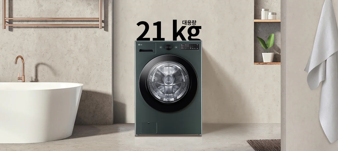 세탁기가 욕실에 놓여 있으며, 세탁기 위에는 21kg 대용량이라는 텍스트가 있습니다. 세탁기 옆에는 욕조와 수건이 걸려 있고, 벽 선반에는 식물과 용기가 놓여 있습니다.