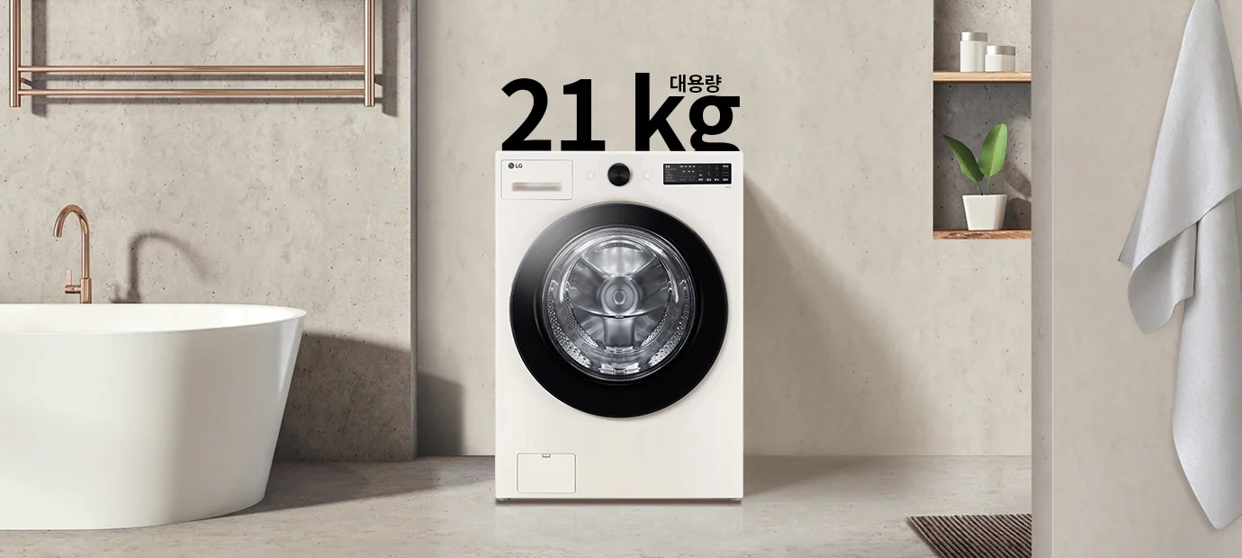 세탁기가 욕실에 놓여 있으며, 세탁기 위에는 21kg 대용량이라는 텍스트가 있습니다. 세탁기 옆에는 욕조와 수건이 걸려 있고, 벽 선반에는 식물과 용기가 놓여 있습니다.