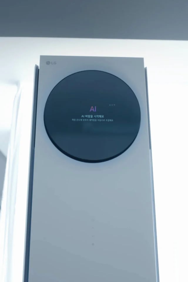 스탠드 에어컨의 상단 전면이 클로즈업되어 보이며, 원형 블랙 디지털 디스플레이 영역 중앙에는 AI 라는 표시가 있고, 그 아래에 AI 바람을 시작해요 라는 문구가 나타나 있습니다. 하단에는 희망 온도에 맞추어 쾌적함을 자동으로 조절해요라는 안내 문구가 작은 글씨로 표시되어 있습니다. 이 이미지는 에어컨의 AI바람 기능이 작동을 시작했음을 사용자에게 알리는 상태 표시 화면을 설명합니다.