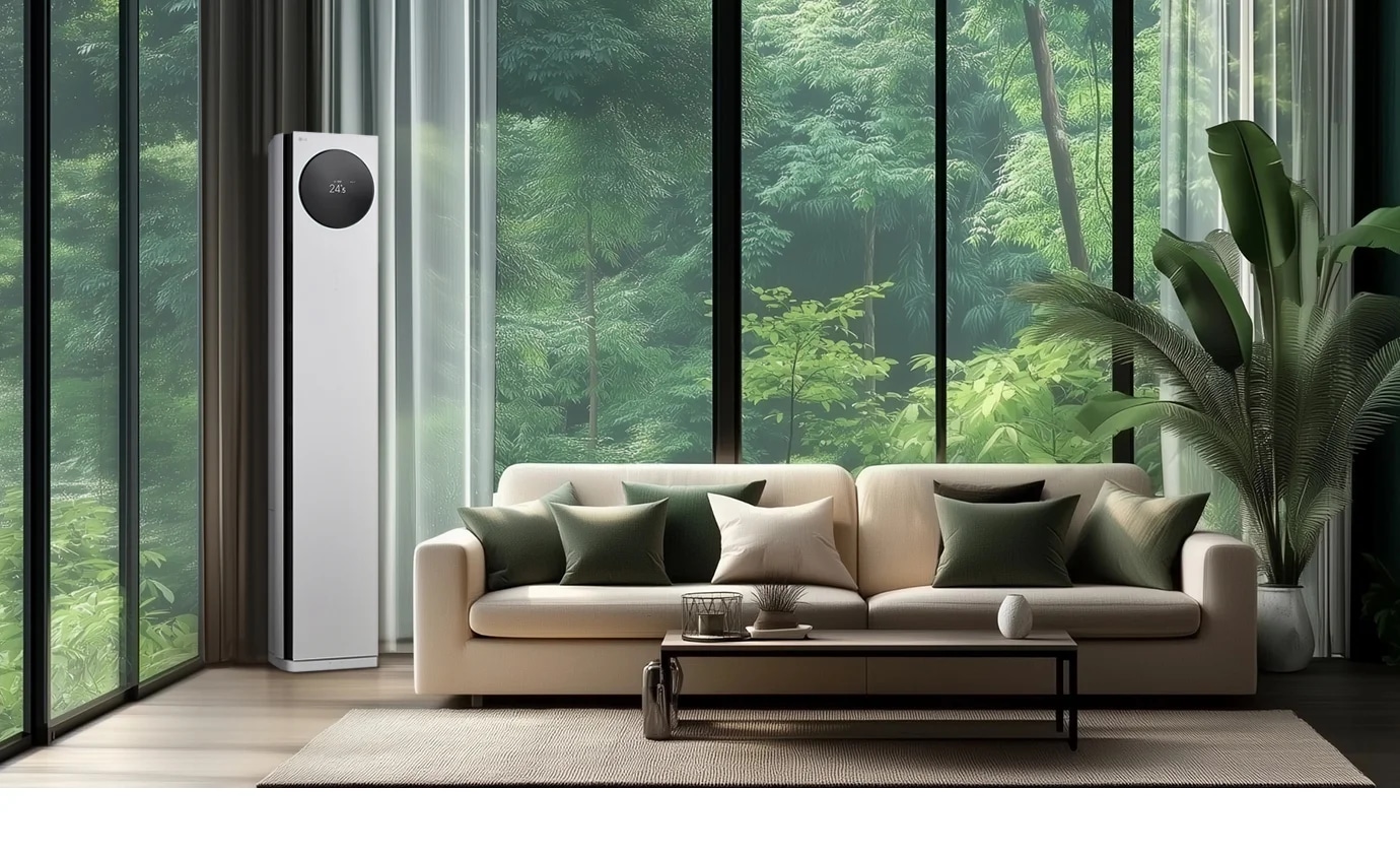 LG 휘센 AI 오브제컬렉션 타워I 에어컨이 거실의 왼쪽 구석에 세워져 있으며, 에어컨의 원형 디스플레이에는 24.5°C라는 숫자가 표시되어 있습니다. 에어컨 옆으로는 큰 창문이 있어 푸른 숲의 풍경이 보이며, 창문 앞에는 베이지색 소파가 놓여 있습니다. 소파 위에는 여러 개의 녹색과 흰색 쿠션이 배열되어 있고, 소파 앞에는 낮은 테이블이 놓여 있습니다. 테이블 위에는 장식품과 책이 놓여 있으며, 오른쪽에는 큰 화분에 심어진 녹색 식물이 배치되어 있습니다.