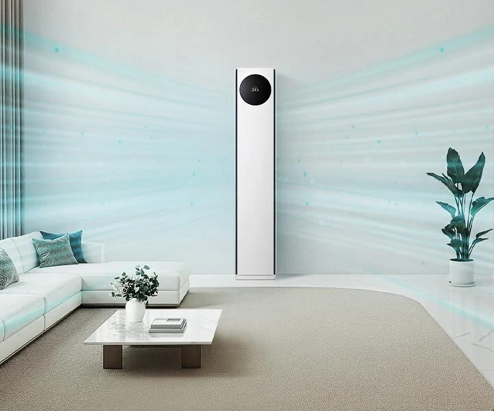 거실 중앙에 세워진 LG 휘센 AI 오브제컬렉션 타워I 에어컨이 보입니다. 에어컨 상단의 원형 블랙 디지털 디스플레이에 온도와 습도 정보가 표시되어 있습니다. 에어컨 양쪽으로 연한 파란색 선 형태의 그래픽이 사방으로 퍼져 벽면을 따라 시원한 공기가 흘러 나가는 모습으로, 공간 전체를 냉방해주는 모습이 시각적으로 표현되어 있습니다. 왼쪽에는 큰 창문을 통해 자연광이 들어오고, 창가 옆에는 밝은 색의 L자형 소파가 배치되어 있으며, 소파 위에는 여러 개의 쿠션이 놓여 있습니다. 소파 앞에는 사각 테이블이 있고, 그 위에는 꽃병과 책이 놓여 있습니다. 오른쪽에는 큰 화분에 심어진 식물이 있으며, 벽 쪽으로는 책장이 보입니다.