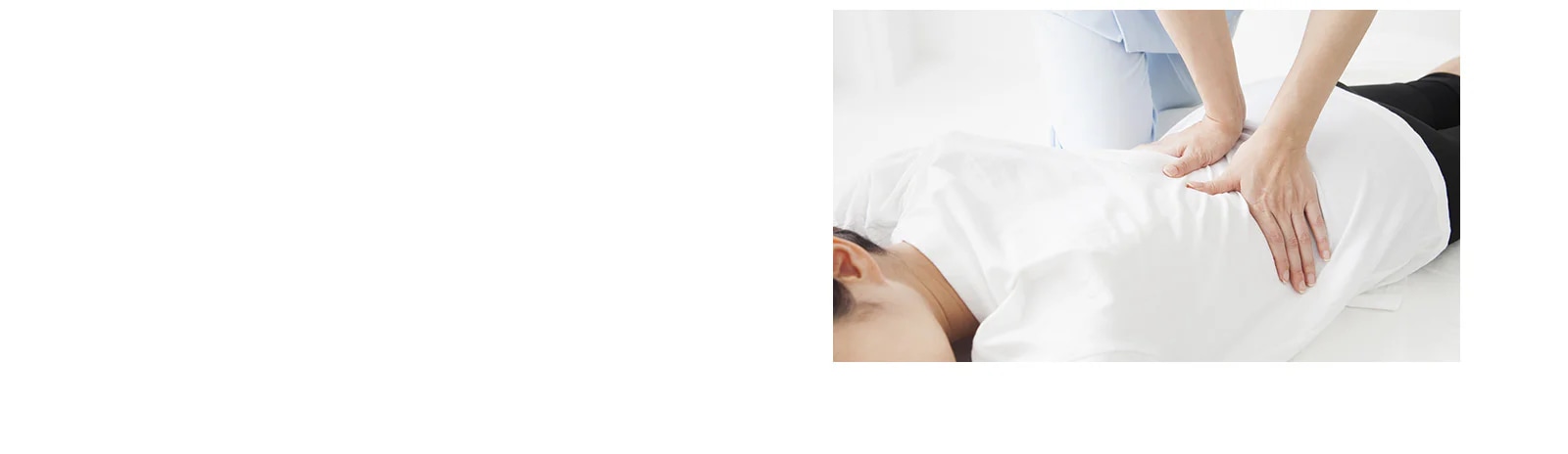 사람이 하얀색 옷을 입고 엎드려 누워 있으며, 다른 사람이 그 위에 손을 올려 마사지를 하고 있습니다. 마사지하는 사람은 하늘색 옷을 입고 있습니다. 배경은 밝고 깨끗한 분위기입니다.